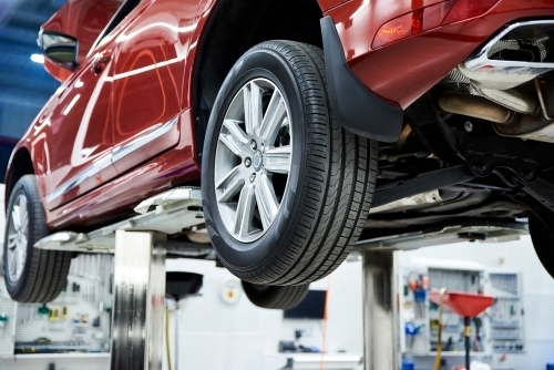 Rød bil hævet på lift til dækskifte og eftersyn hos A2 Dry Wash